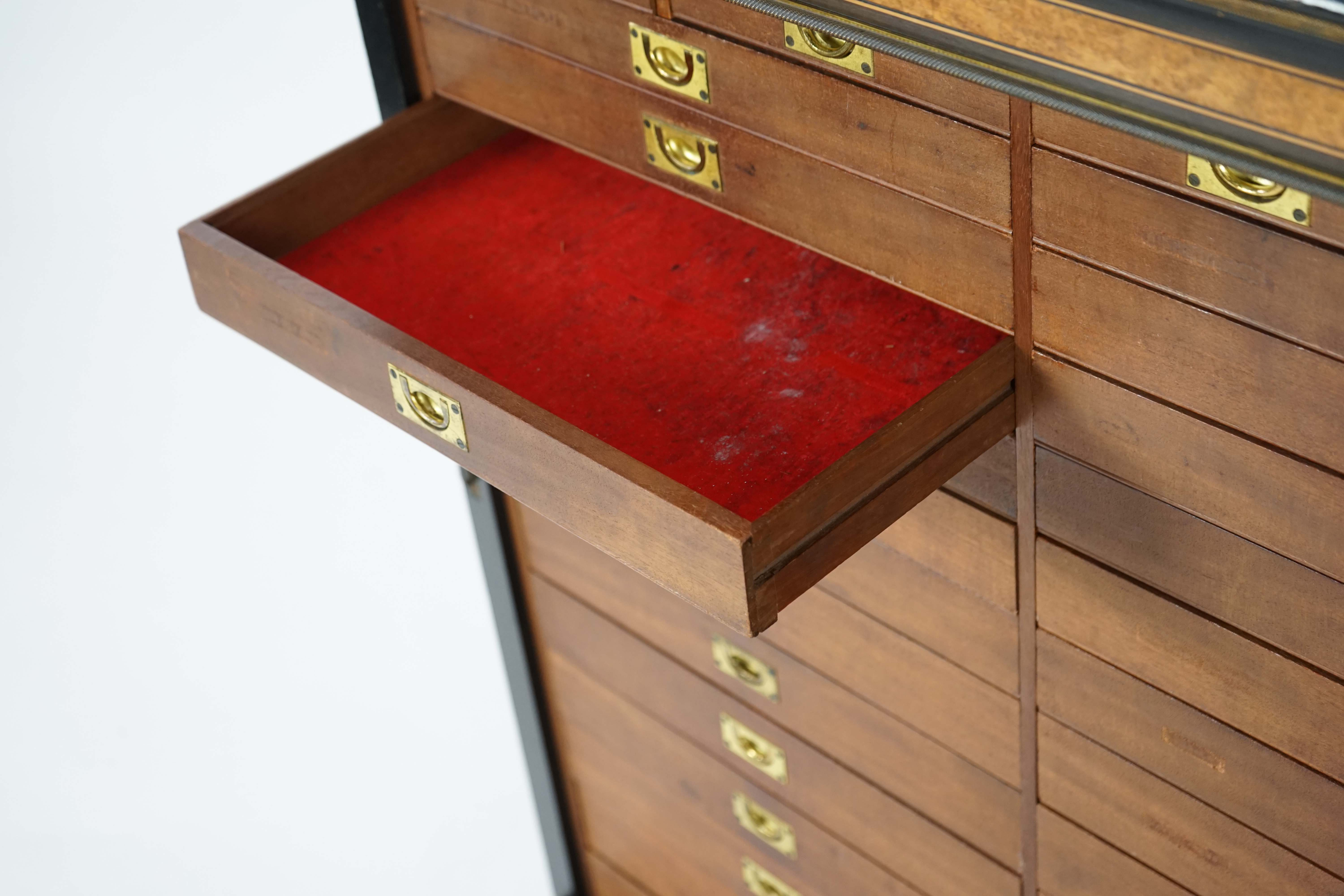 A Victorian ebony banded amboyna wood collector's cabinet, by Holland & Sons, with inverted breakfront top and single mirrored door enclosing four frieze and two banks of thirteen graduated drawers fitted with recessed b